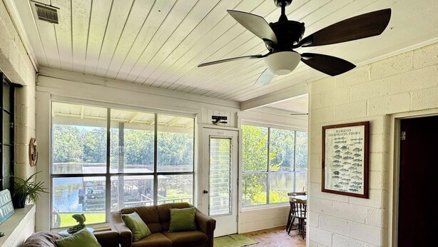 A spacious living room with a large window, a ceiling fan, and a tiled floor. - Lake Talquin Fisherman's Paradise (Tallahassee)