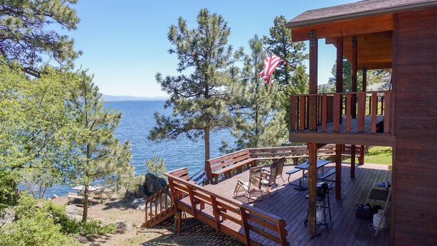 A wooden deck with outdoor seating and a flag. - The west shore getaway on Canyon Ferry. (Helena)