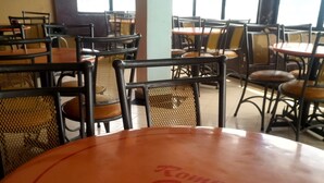 A round table with "Romani Guest" written on it, surrounded by chairs with mesh backs. - Romani Resort (Nakuru)
