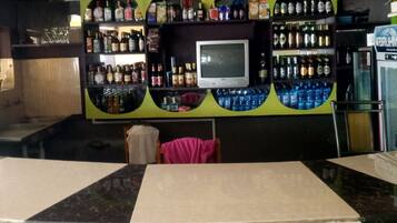 A bar area with shelves of liquor bottles, a television, and a refrigerator.