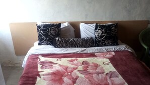 A bed with a floral bedspread, white pillows, and a zebra-patterned pillow. - Romani Resort (Nakuru)