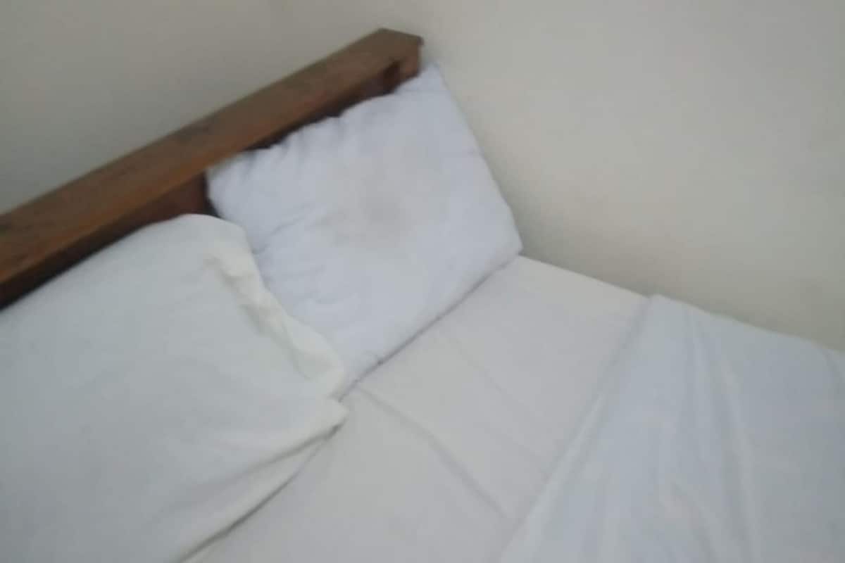 Una cama con ropa blanca y cabecera de madera.