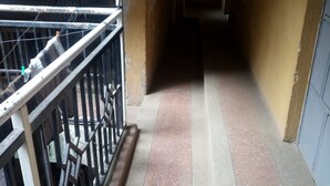 Un couloir étroit, avec une rambarde métallique d’un côté et un sol en béton.