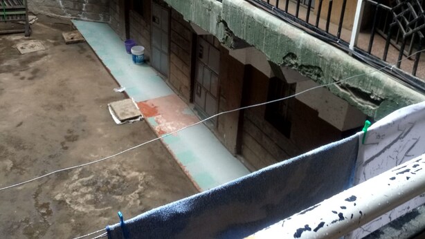 Une cour avec un balcon, une échelle et un réservoir d’eau.