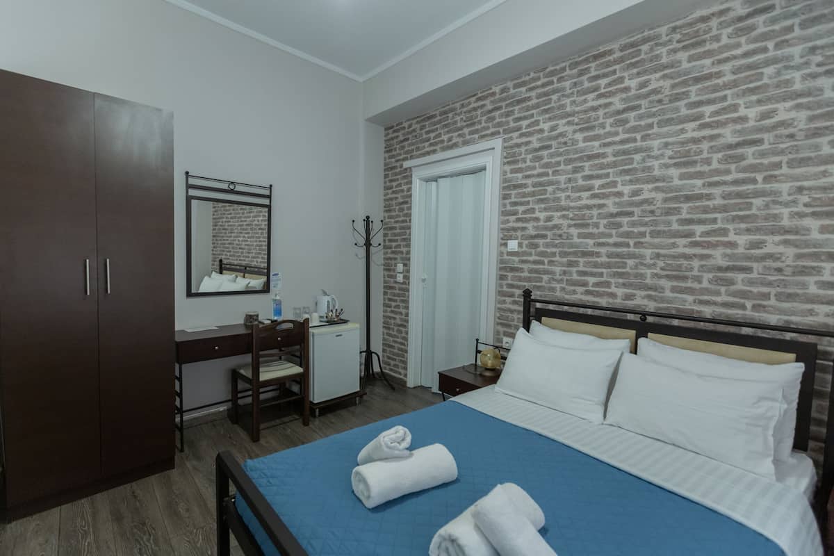 Ein Hotelzimmer mit Bett, Schreibtisch, Kleiderschrank und einer Backsteinwand.