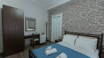 Habitación de hotel con cama, escritorio, armario y pared de ladrillo.
