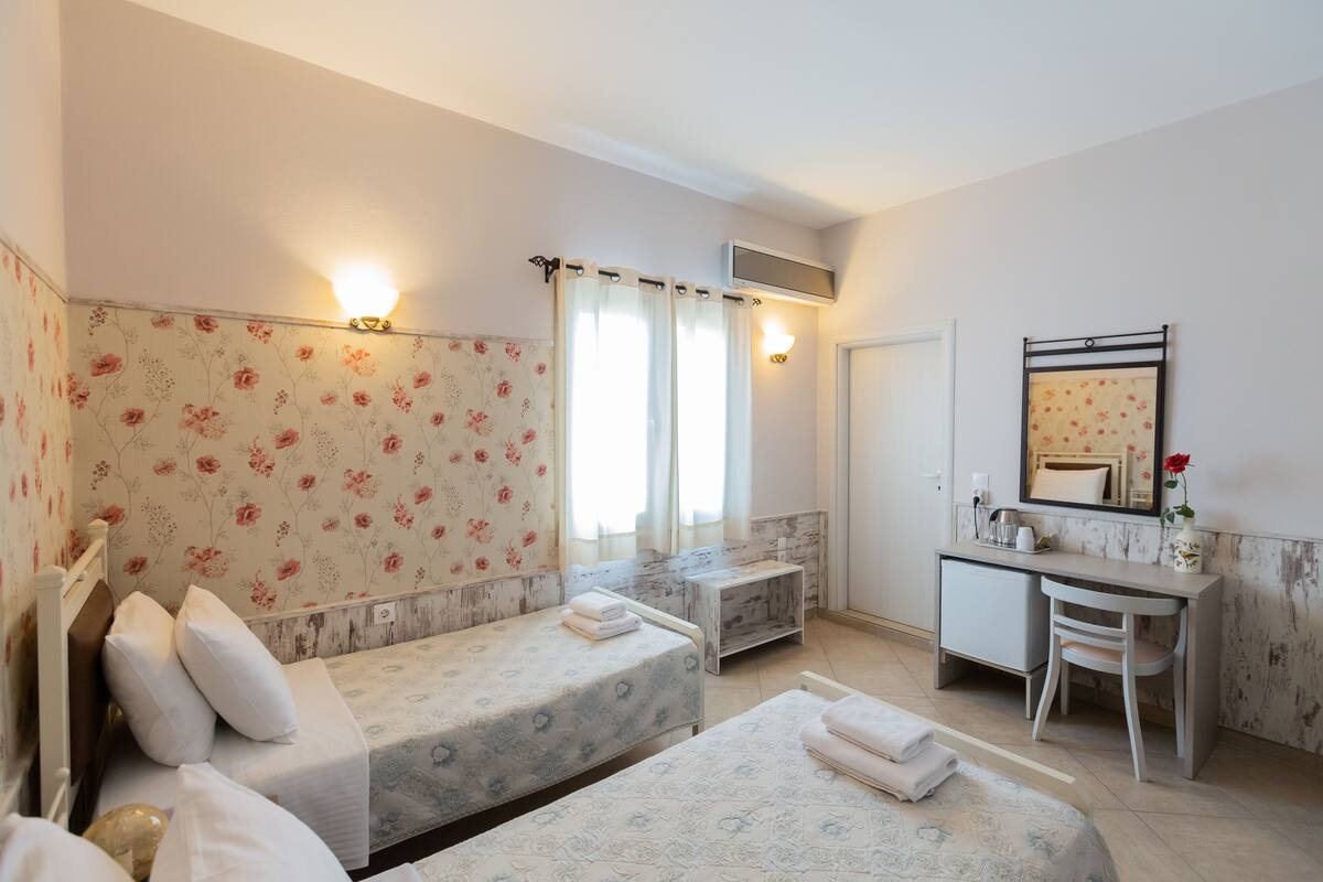 Ein Schlafzimmer mit zwei Betten, einem Schreibtisch, einem Stuhl und einer Dusche.