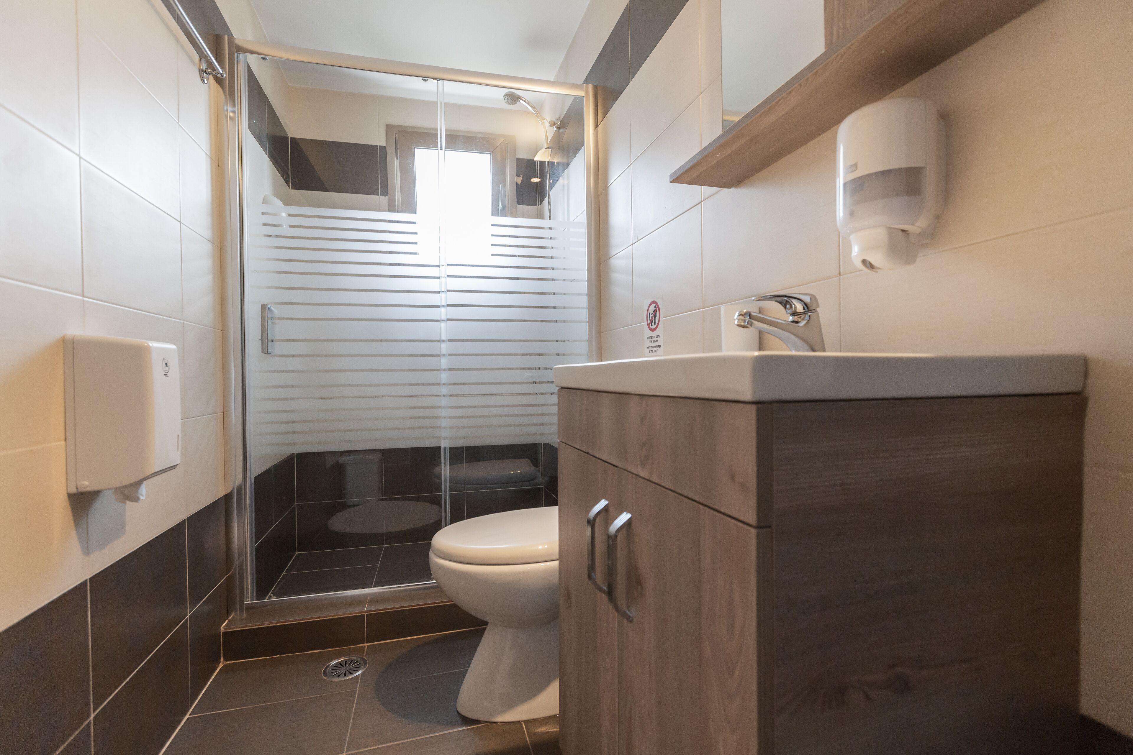 Une salle de bain moderne avec une douche à parois de verre, des toilettes et un meuble-lavabo en bois avec un évier.