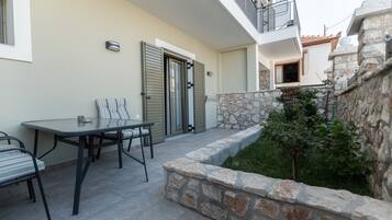 An outdoor patio with a table and chairs, a stone wall, and a door.