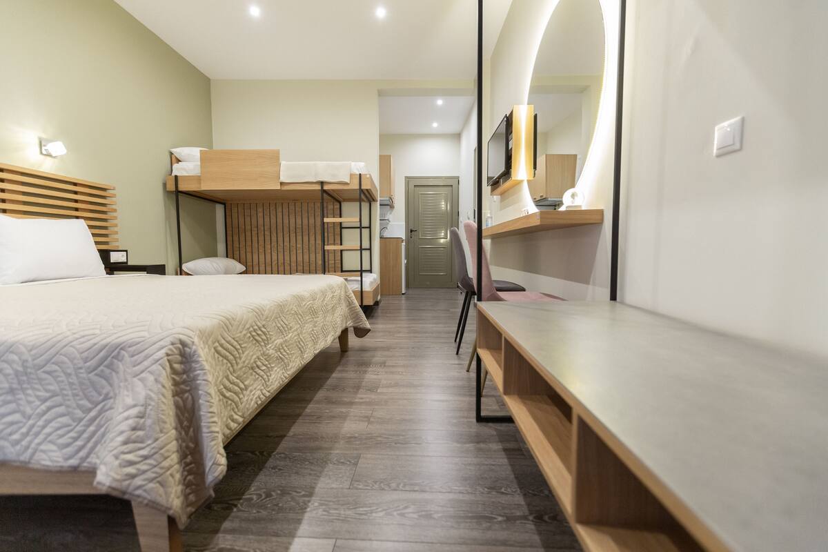 Ein Hotelzimmer mit Etagenbett, Schreibtisch, Stuhl, Fernseher und Spiegel.