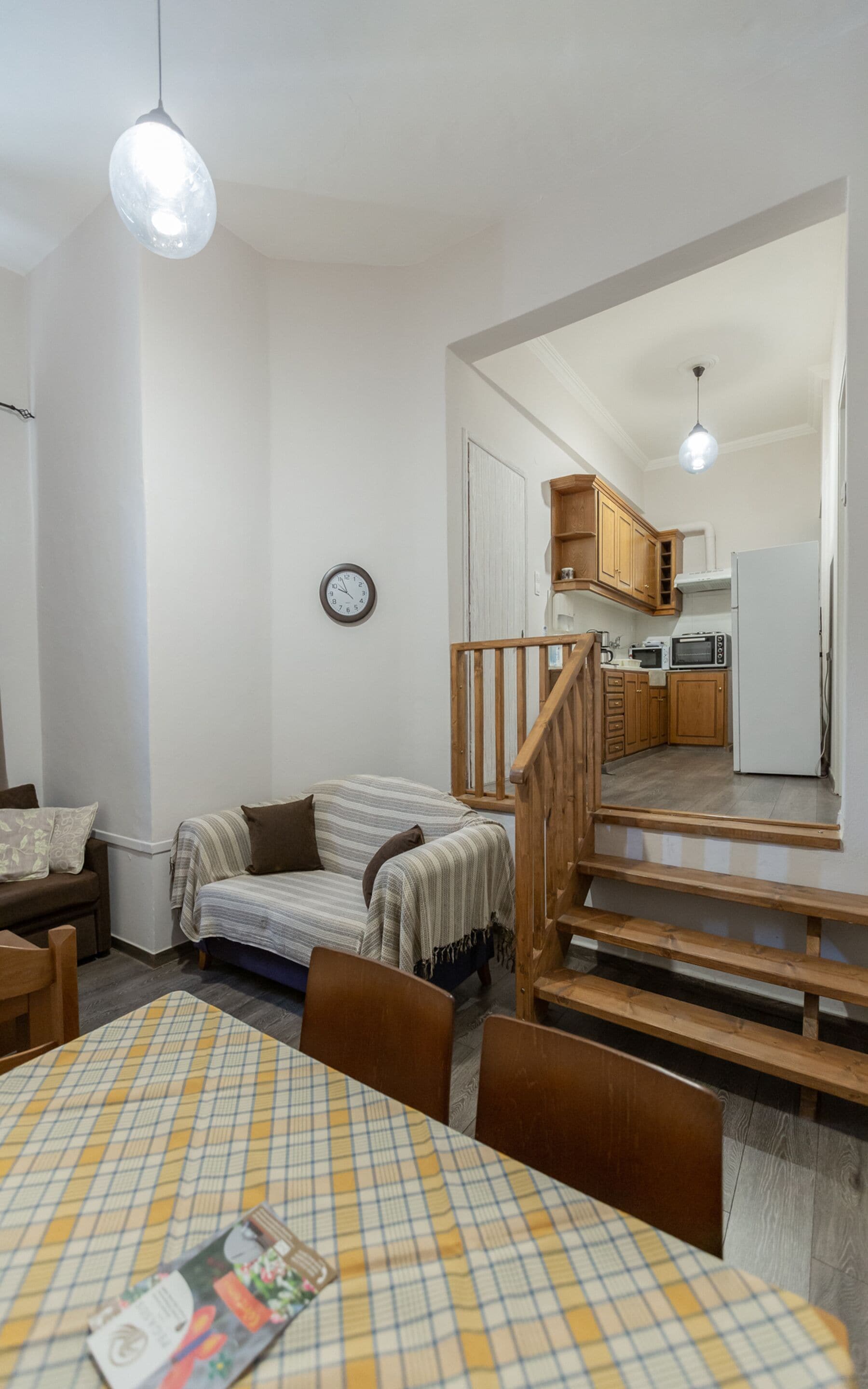 A compact living space with a dining area, a kitchen, and a staircase.