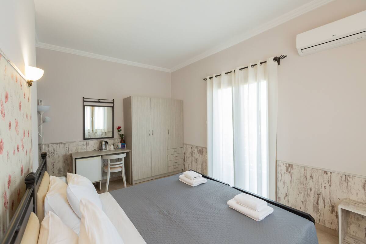 Ein Hotelzimmer mit Bett, Schreibtisch, Stuhl, Kleiderschrank und einem Fenster mit Vorhängen.