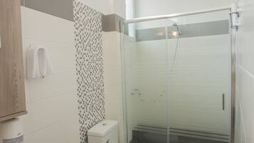 Et moderne badeværelse med bruseniche, toilet og håndvask.