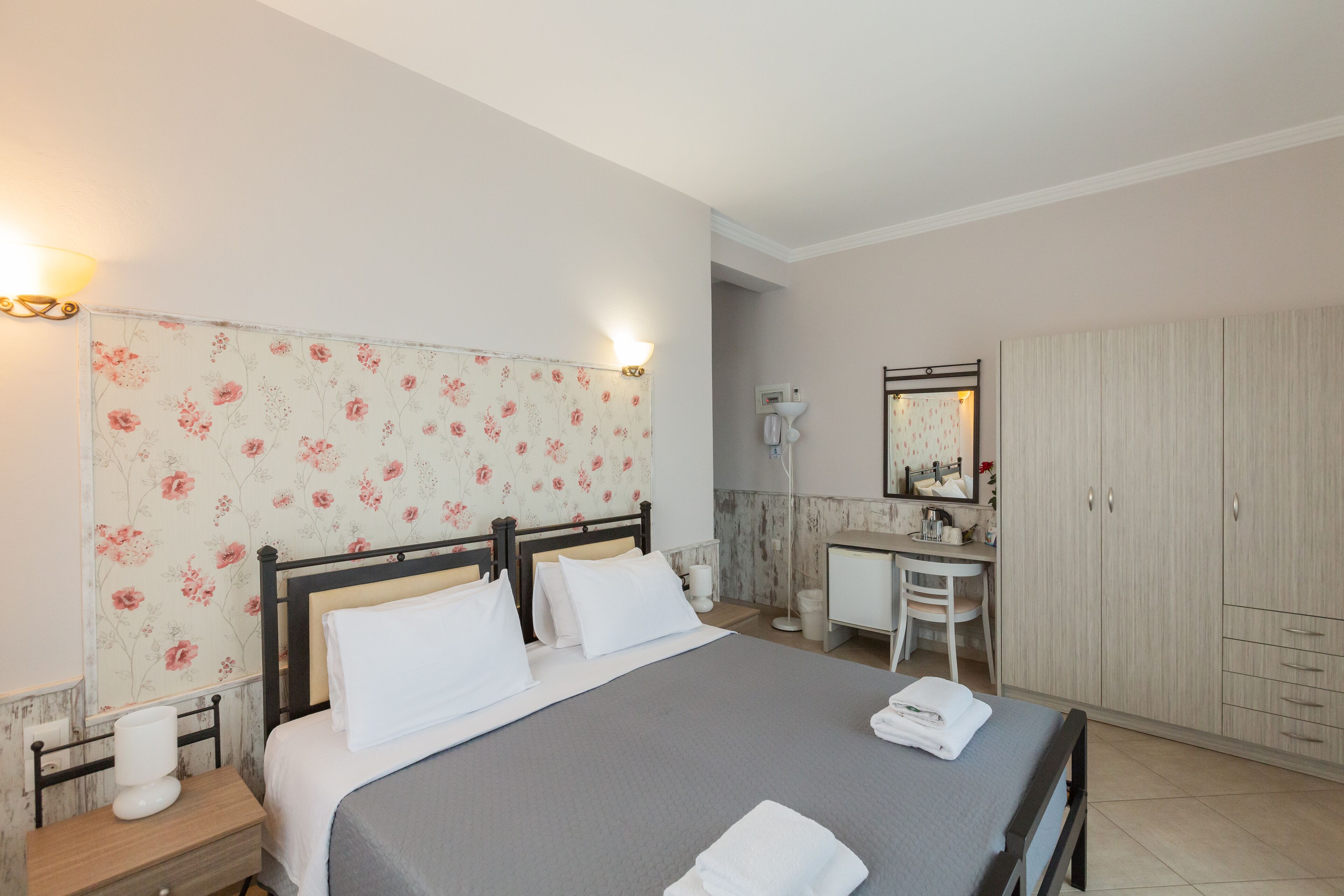 A neatly arranged bedroom with a bed, bedside table, and a small desk with a chair.