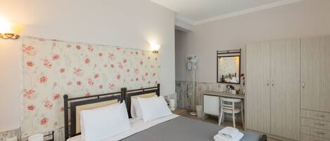 A neatly arranged bedroom with a bed, bedside table, and a small desk with a chair.