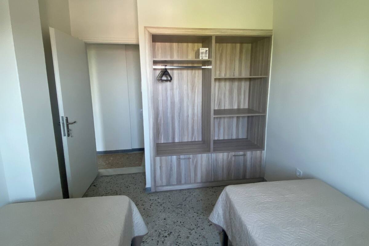 Ein Zimmer mit zwei Betten, einem Kleiderschrank und einer Tür zu einem anderen Raum.