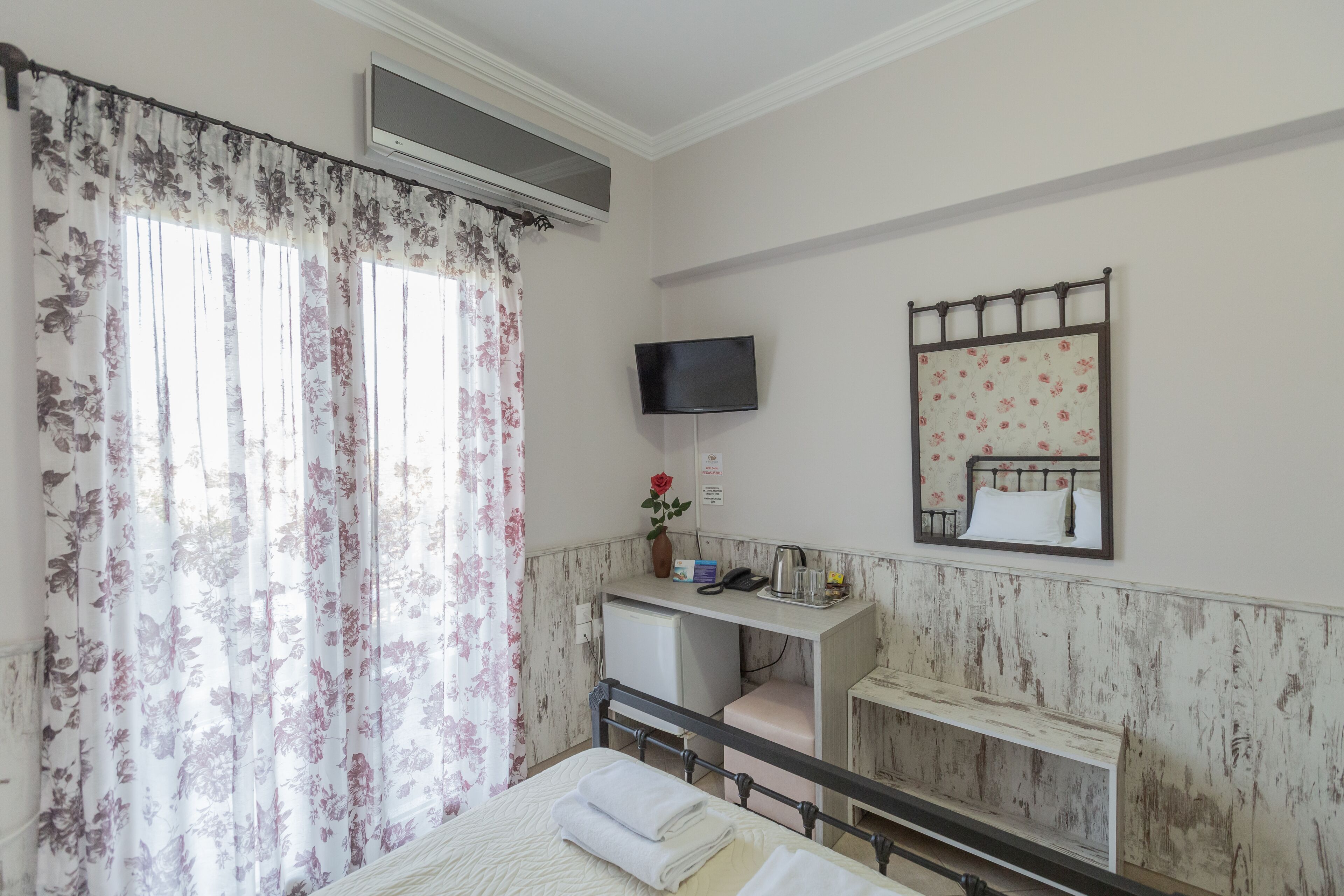 Une chambre à coucher avec un lit, un bureau, une télévision et un miroir.