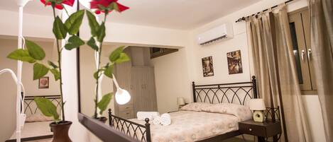 A bedroom with a bed, bedside table, lamp, and a mirror reflecting the room.