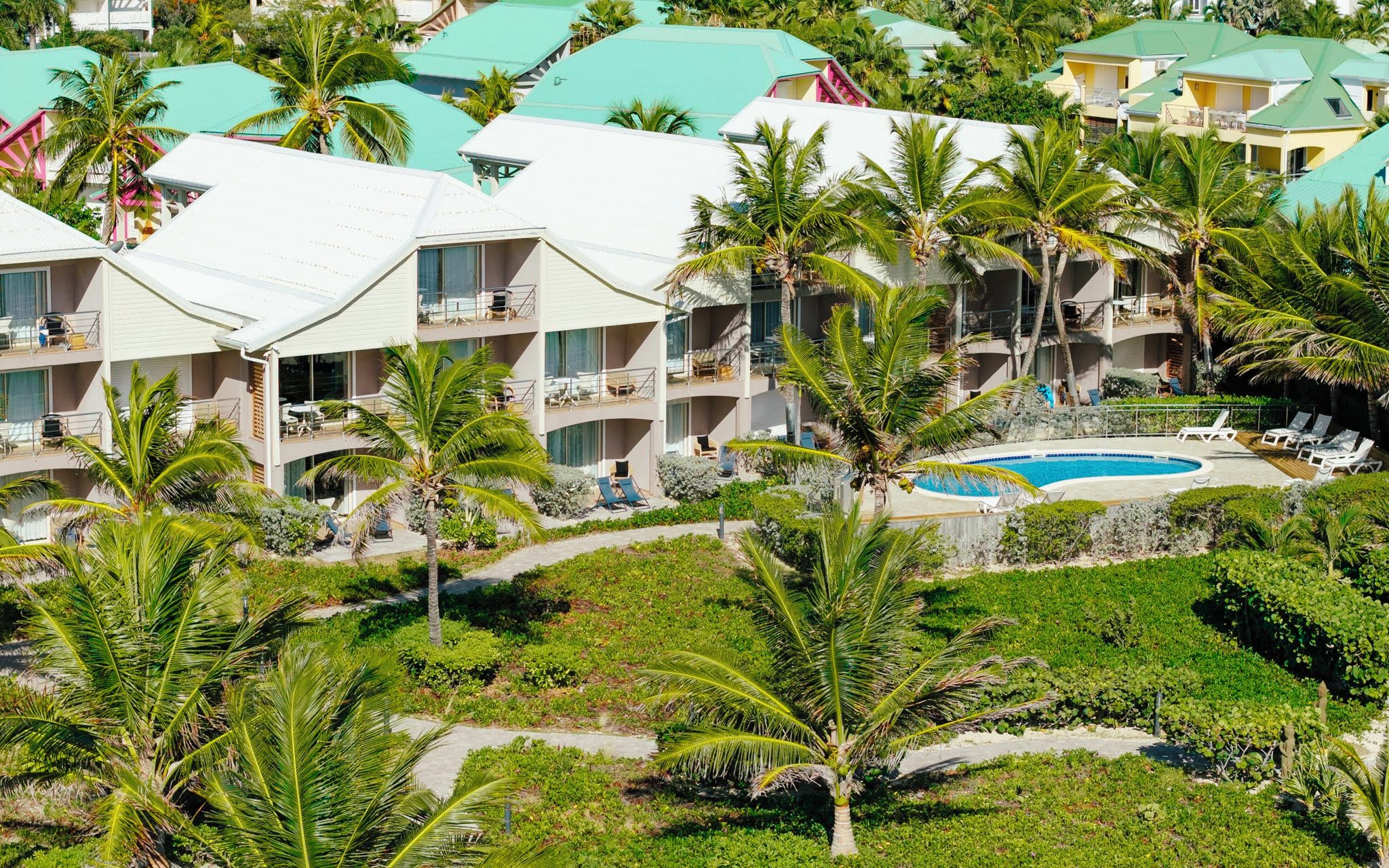 Un resort con edificios de varios pisos, una piscina y abundante vegetación.