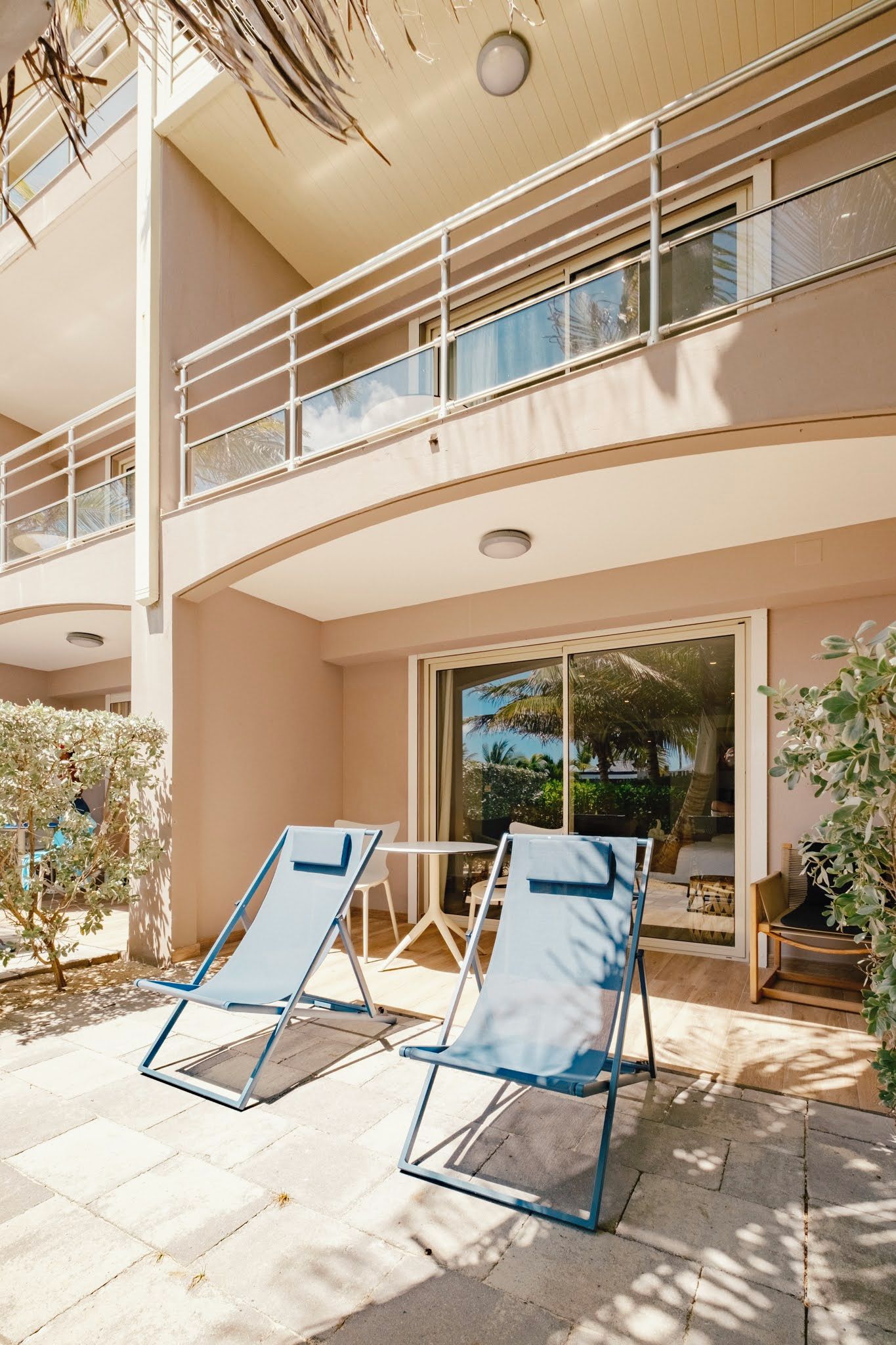 A modern building with a balcony, outdoor seating area, and large windows.
