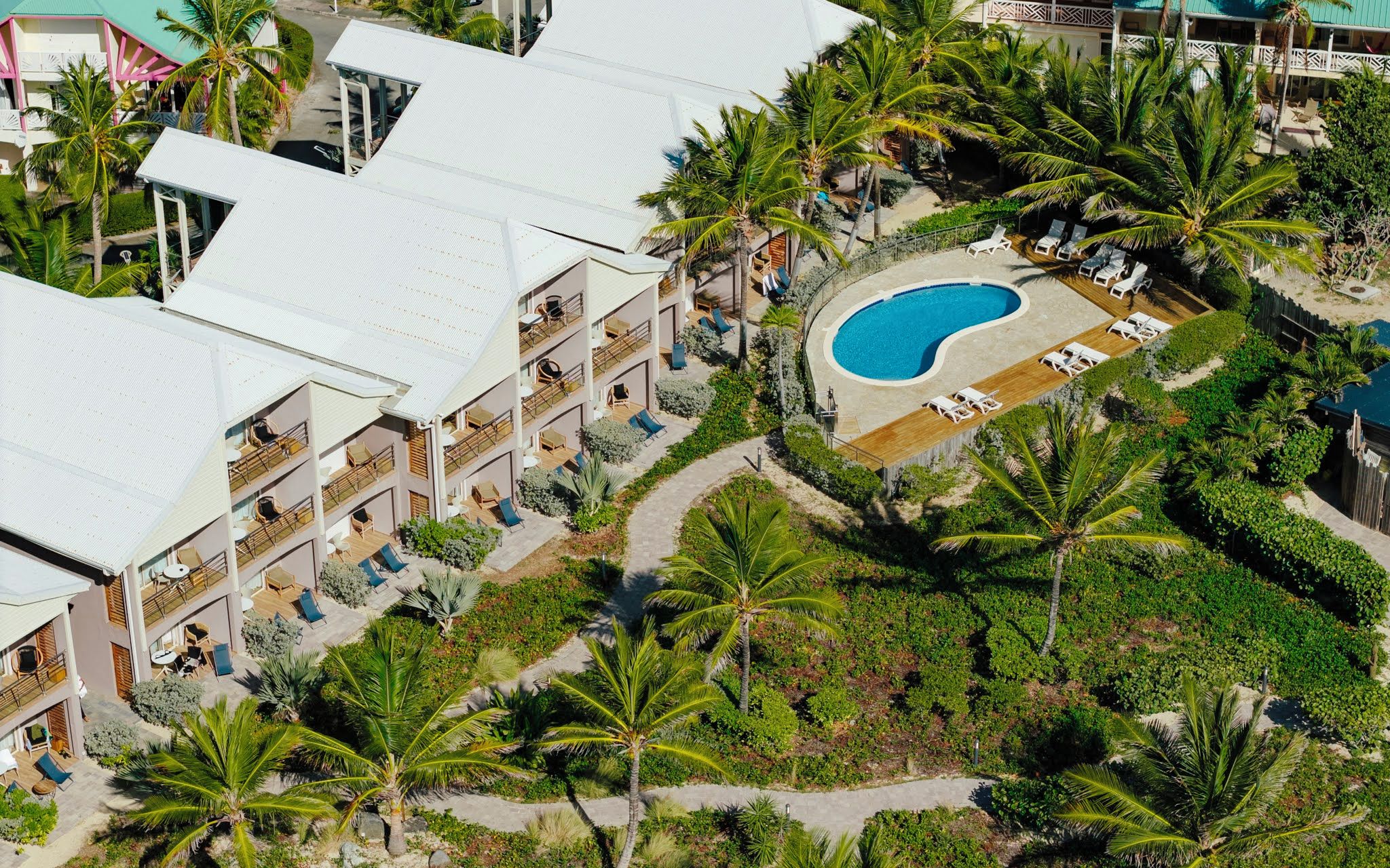 A resort with multiple balconies, a swimming pool, and lush tropical landscaping.