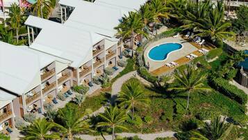 A resort with multiple balconies, a swimming pool, and lush tropical landscaping.