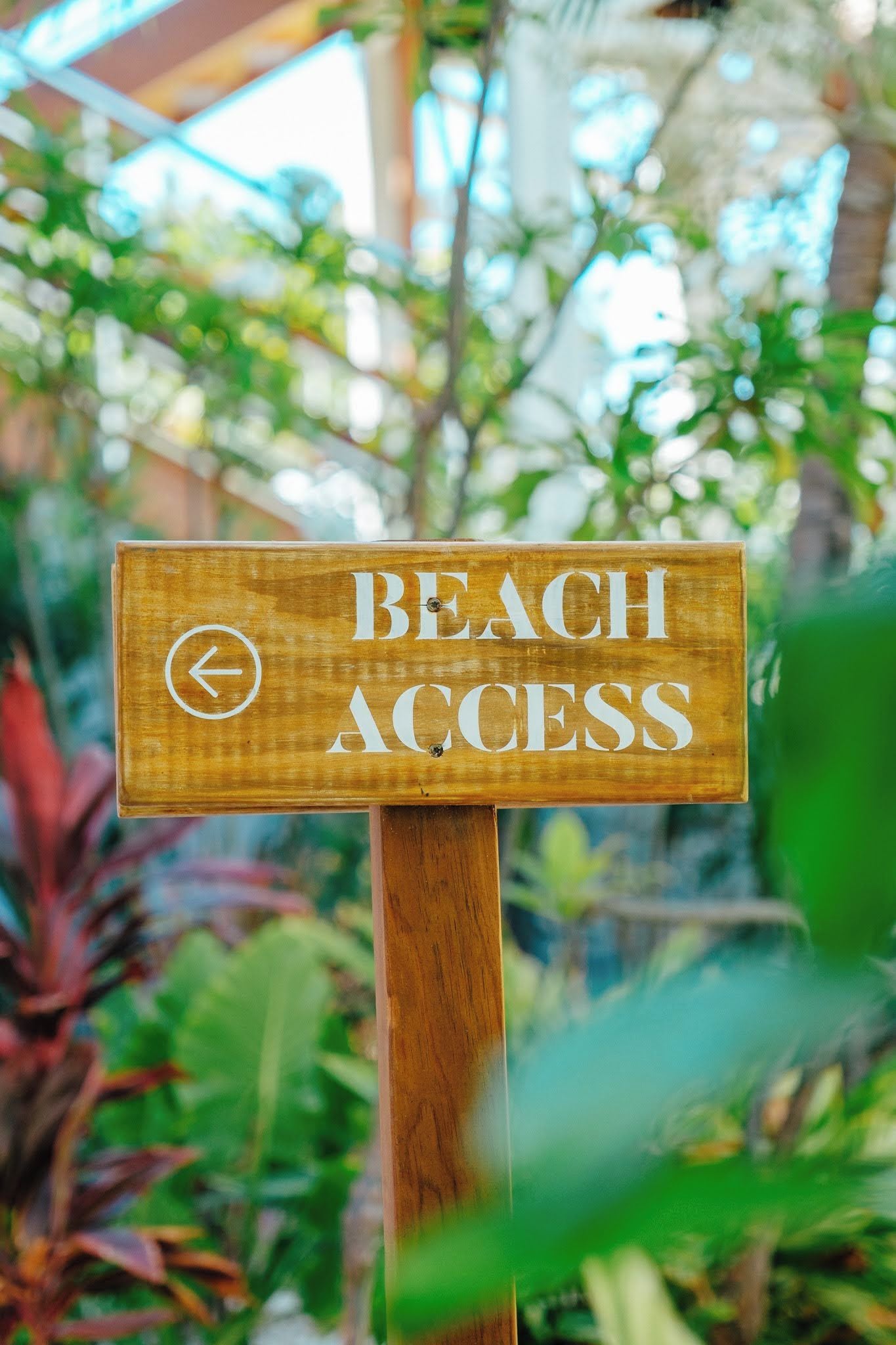 A wooden sign with 'BEACH ACCESS' and a left-pointing arrow, indicating the direction to the beach.