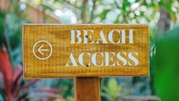 A wooden sign with 'BEACH ACCESS' and a left-pointing arrow, indicating the direction to the beach.