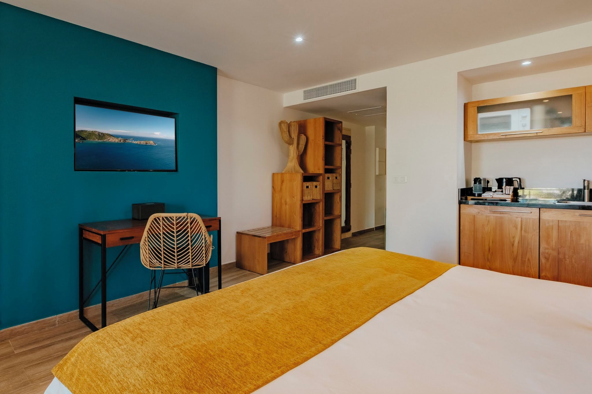 A room with a bed, a desk, a chair, a wardrobe, and a kitchenette.