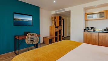 A room with a bed, a desk, a chair, a wardrobe, and a kitchenette.