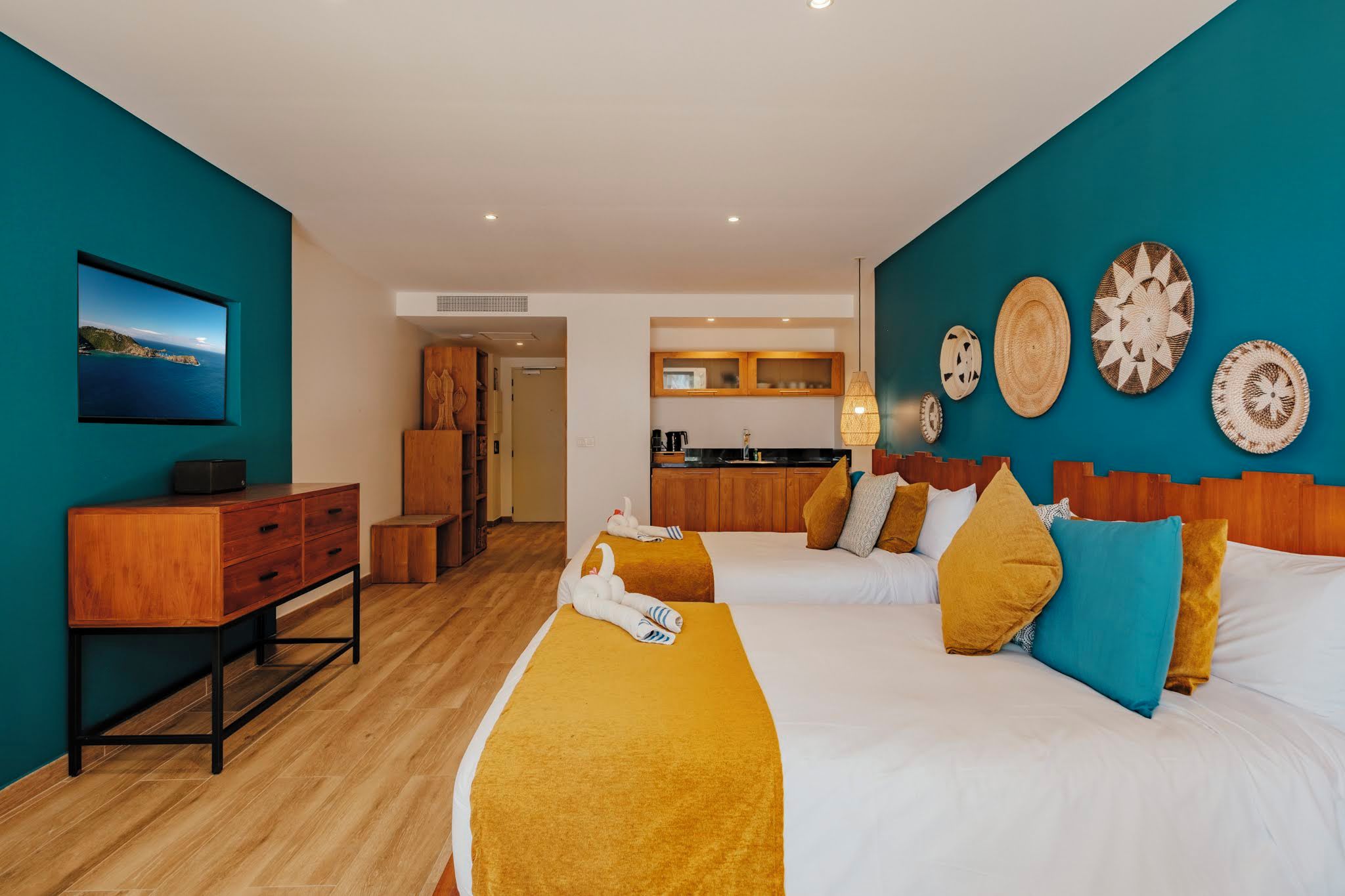 Una habitación de hotel con una cama, un escritorio, un televisor y una kitchenette.