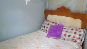 Una cama individual con una colcha floral, un cojín morado y un dosel.
