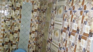 Un baño con inodoro, baldosas estampadas y un secador de pelo fijado al techo.