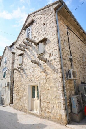 A stone building with a staircase leading to the entrance, a satellite dish, and an air conditioning unit.
