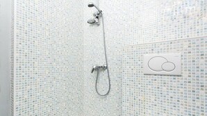 Ducha con pared de mosaicos y panel de control de diseño circular.