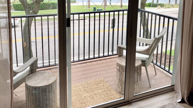A balcony with a view of a lake, a street, and a parking area.