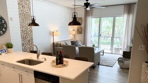 A modern kitchen with a central island, stainless steel appliances, and a dining area with a sofa and chairs.