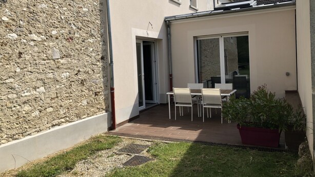 A courtyard with a table and chairs, a potted plant, and a stone wall. - Calm and relaxation in Champagne (Verneuil)