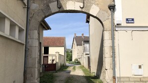 A narrow alleyway with an arched stone gateway, leading to a building with a tiled roof. - Calm and relaxation in Champagne (Verneuil)