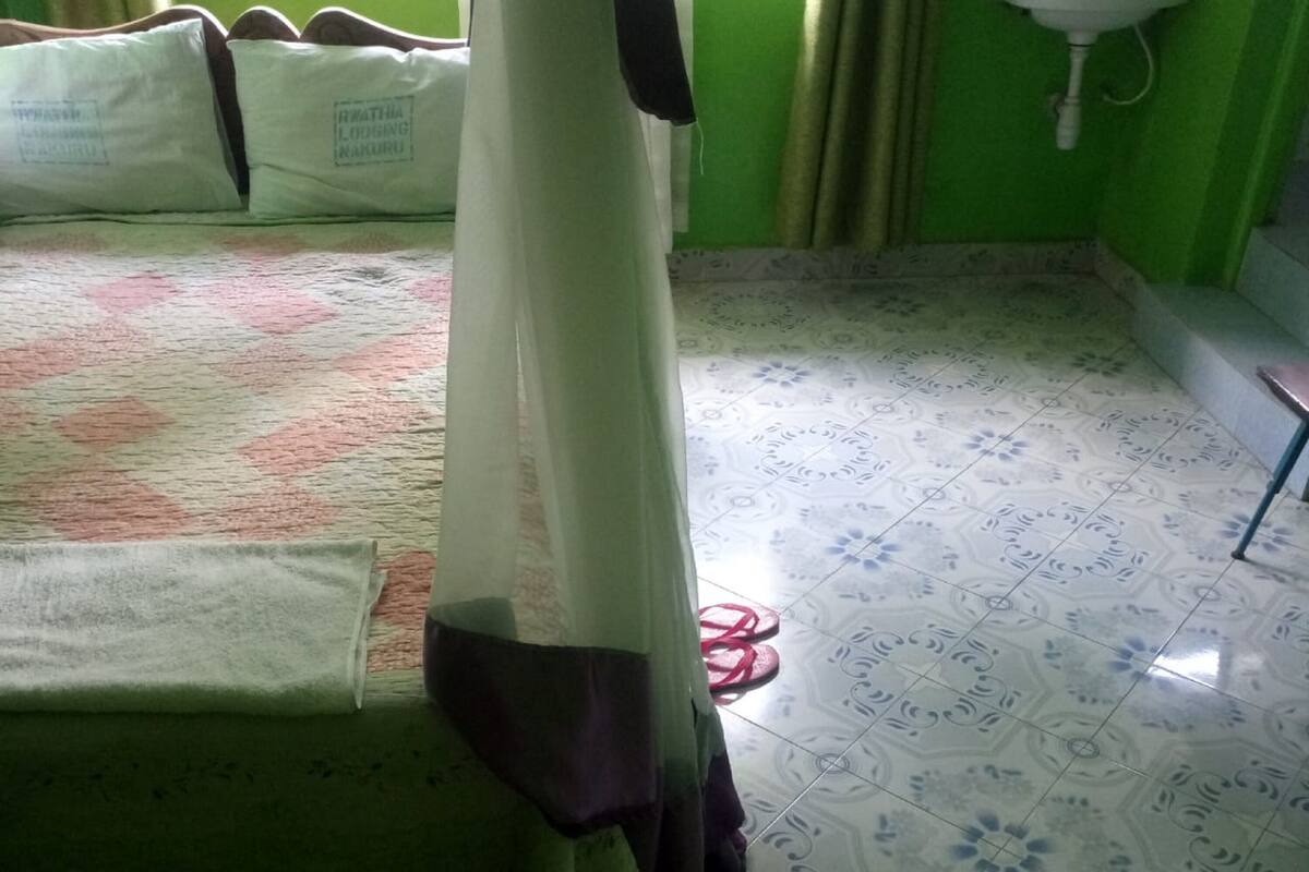 A room with a bed, a curtain, a sink, and patterned floor tiles.