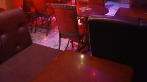 L’intérieur d’un restaurant, éclairé d’une lumière rouge, avec de nombreuses tables et chaises, et un panneau sur le mur portant l’inscription « TUSKER ».