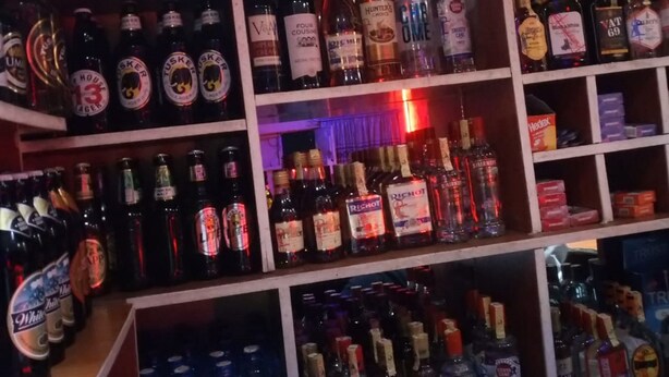 Un bar dont les étagères sont remplies de différentes bouteilles d’alcool, notamment de whisky, de vodka et de gin.