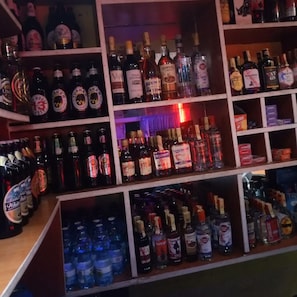 A bar with shelves stocked with various liquor bottles, including whiskey, vodka, and gin. - Rwathia Club Boarding & Lodging (Nakuru)