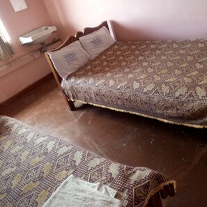 Una habitación con una cama, una mesita de noche y un estante en la pared.