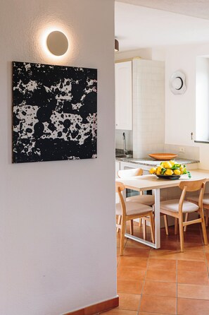 A modern kitchen with white cabinets, a round light fixture, and a black and white abstract painting on the wall.