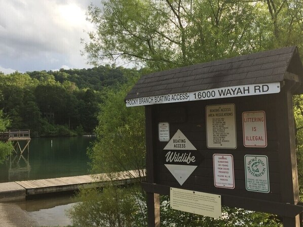 A wooden signboard with multiple notices including 'Rocky Branch Boating Access' and 'Wildlife' warnings.