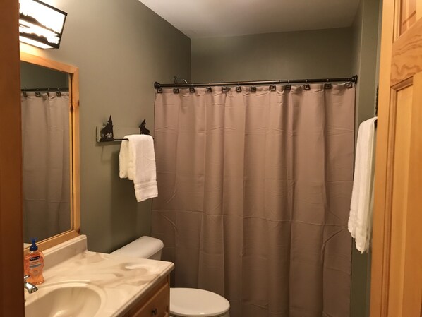 Une salle de bain avec un rideau de douche beige, un lavabo blanc et des toilettes.