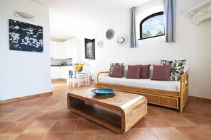 A living room with a sofa, coffee table, and a view of the kitchen.