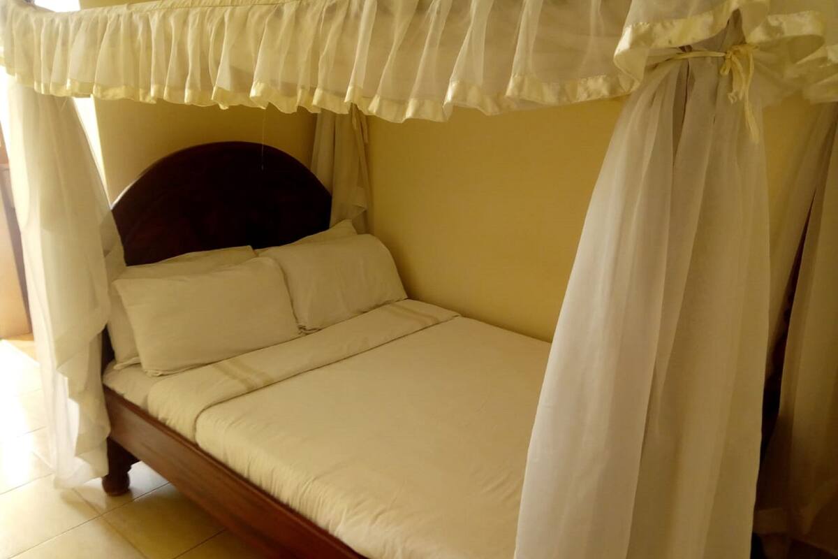 Un lit à baldaquin, avec une tête de lit en bois et une literie blanche.