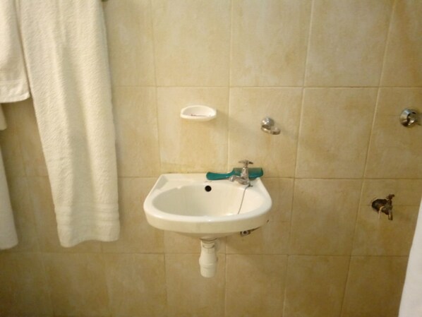 A bathroom with a white sink, a towel hanging on the wall, and a soap dish.